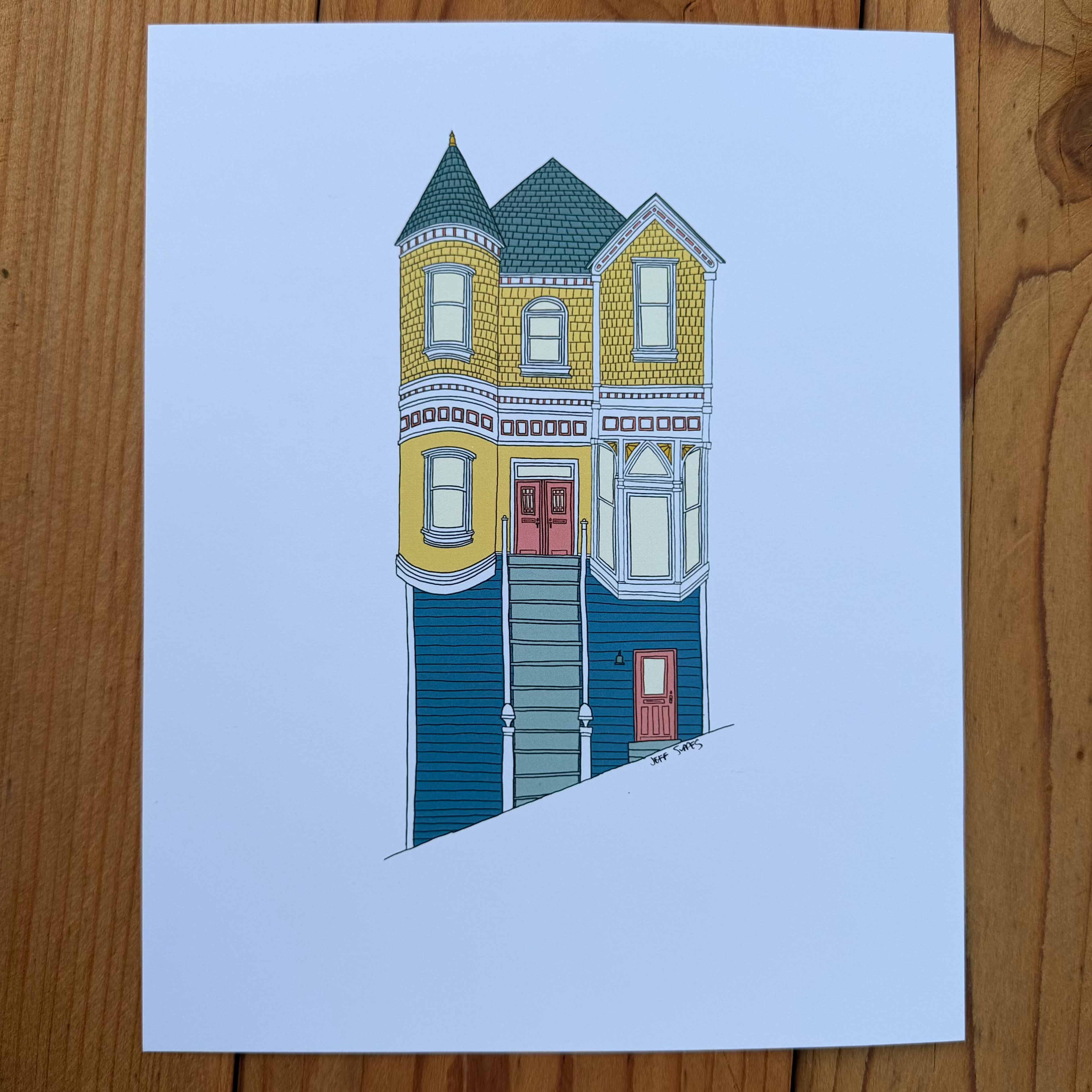 Illustration of a two-story house with yellow and blue exterior on a light blue background, placed on a wooden surface.
